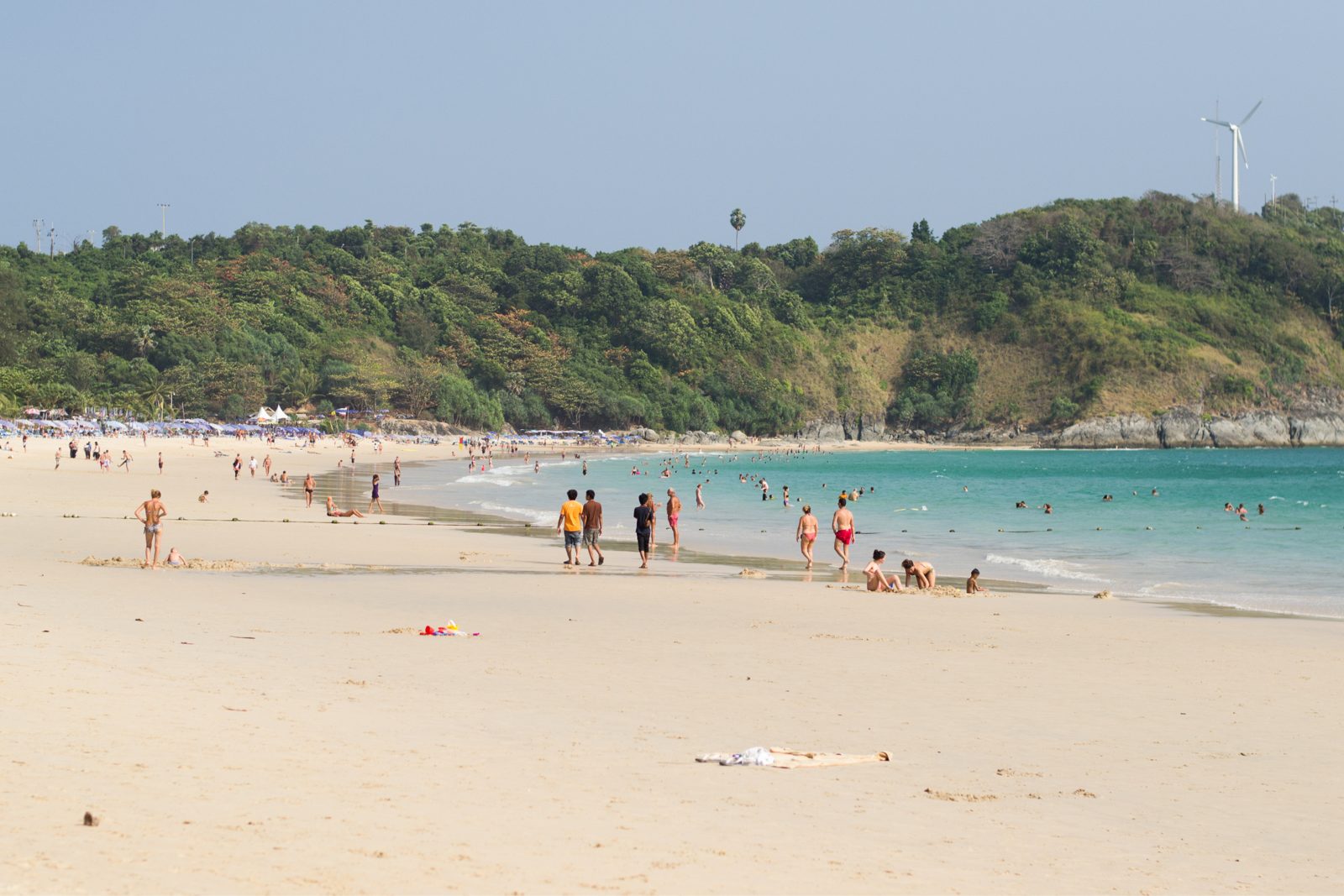 Plaża Nai Harn na Phuket o zachodzie słońca z plażowiczami i jachtami na horyzoncie