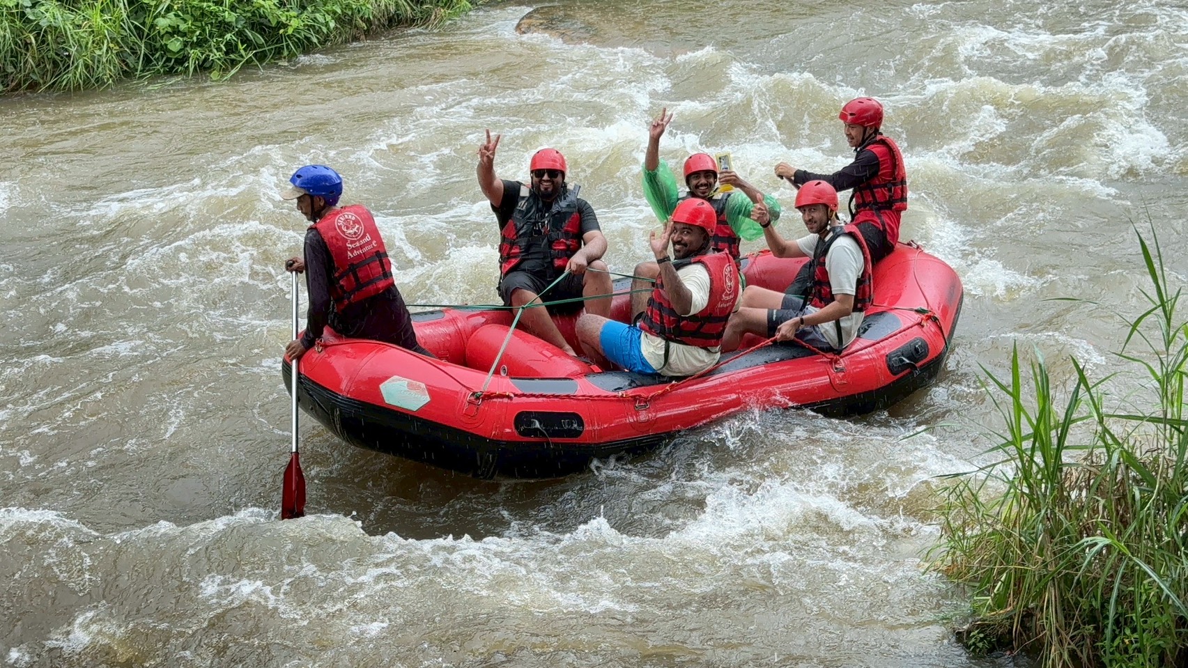 Rafting – grupa w pontonie na bystrzu, ręce w górze